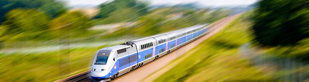 Zug fährt mit schneller Geschwindigkeit auf Gleisen