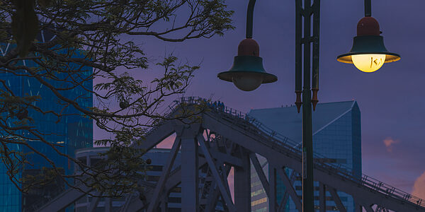 Städtische Straßenbeleuchtung bei Dämmerung mit leuchtender Laterne vor moderner Architektur