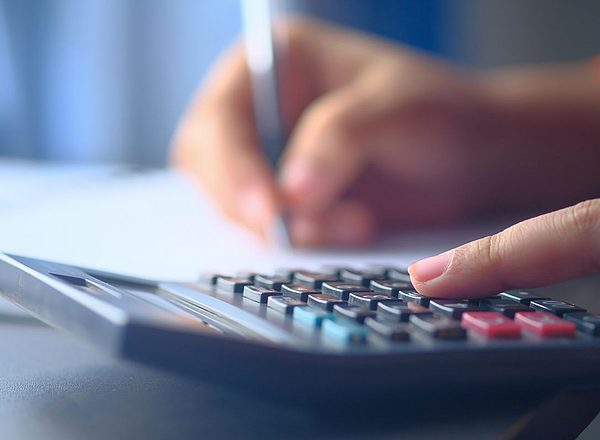 Nahaufnahme einer Hand die auf einem Taschenrechner tippt