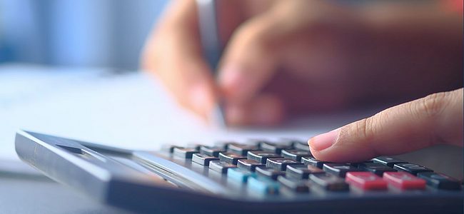 Person berechnet Spesen händisch mit Taschenrechner